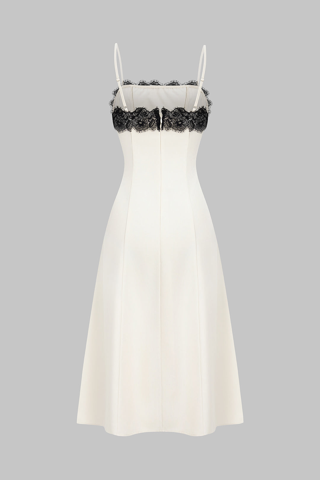 Sleeveless white midi dress featuring delicate black lace, ideal for a chic party or formal event.