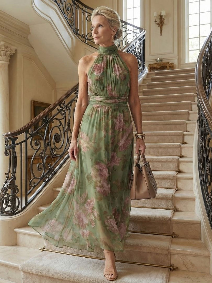 Woman models a flowy sage green floral halter midi dress, perfect for summer parties & elegant events.