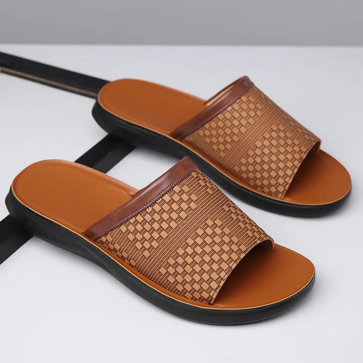 Top view of a pair of men's black woven slip-on slides, comfortable open-toe footwear.