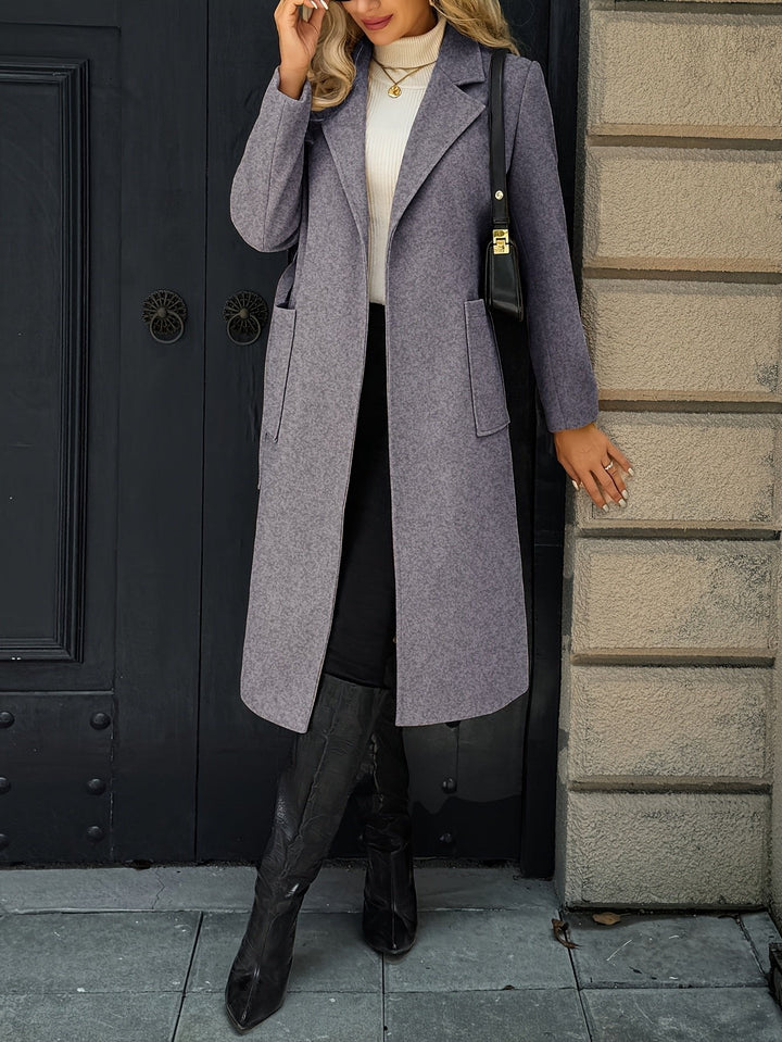 Woman with hands in pockets of a long belted trench coat. Elegant tailored style, sophisticated outerwear.
