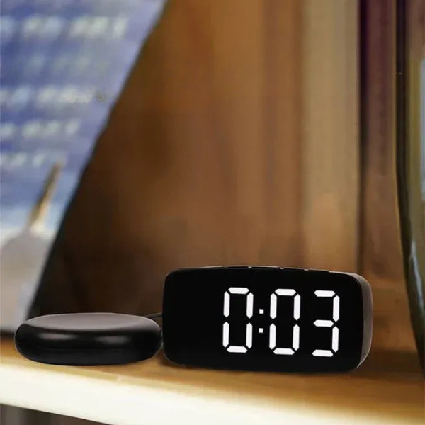 Bed shaker for heavy sleepers, shown under a pillow, connected to a vibrating alarm clock. Effective wake-up aid.