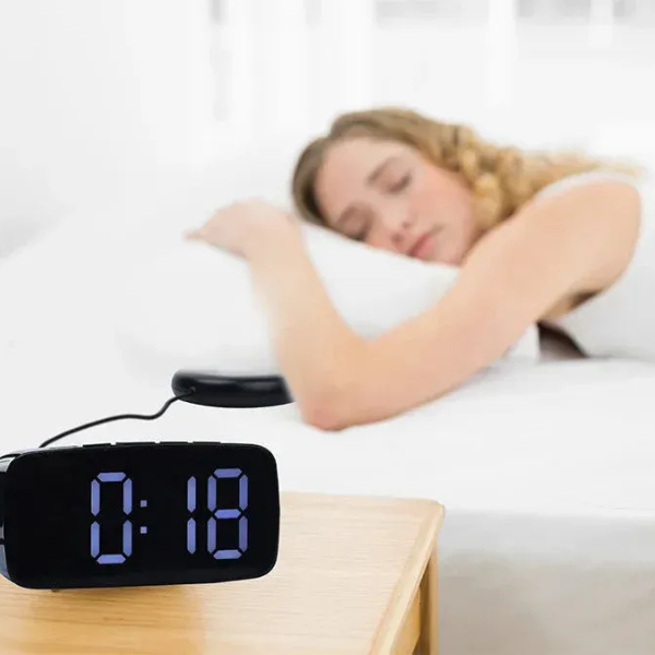 Sleek black digital vibrating alarm clock on a nightstand. Bed shaker for seniors & deep sleepers ensures you wake up.