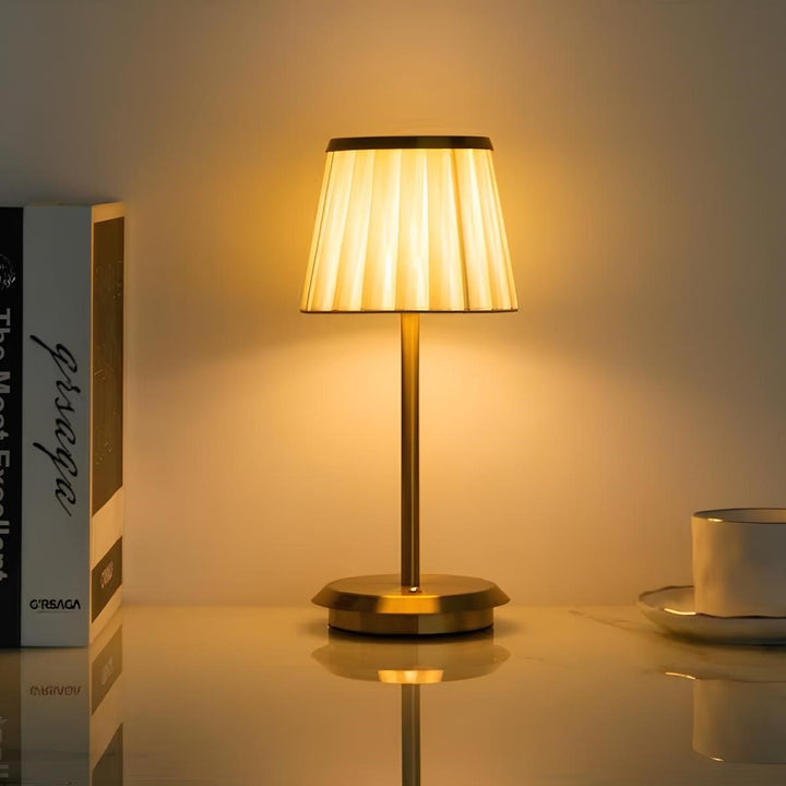Portable rechargeable LED table lamp, elegant fabric shade, brass base. Dimmable touch control for modern home decor.