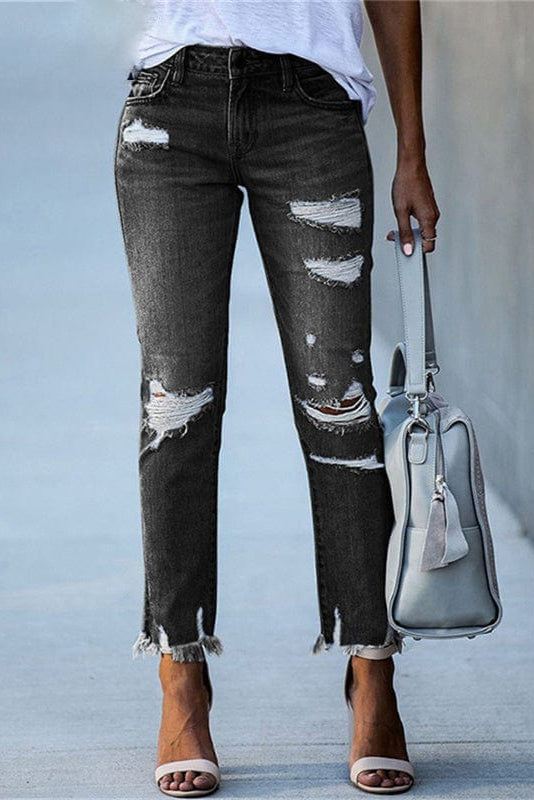 Close-up of ripped details on women's distressed straight leg jeans, showcasing raw hem and vintage wash.