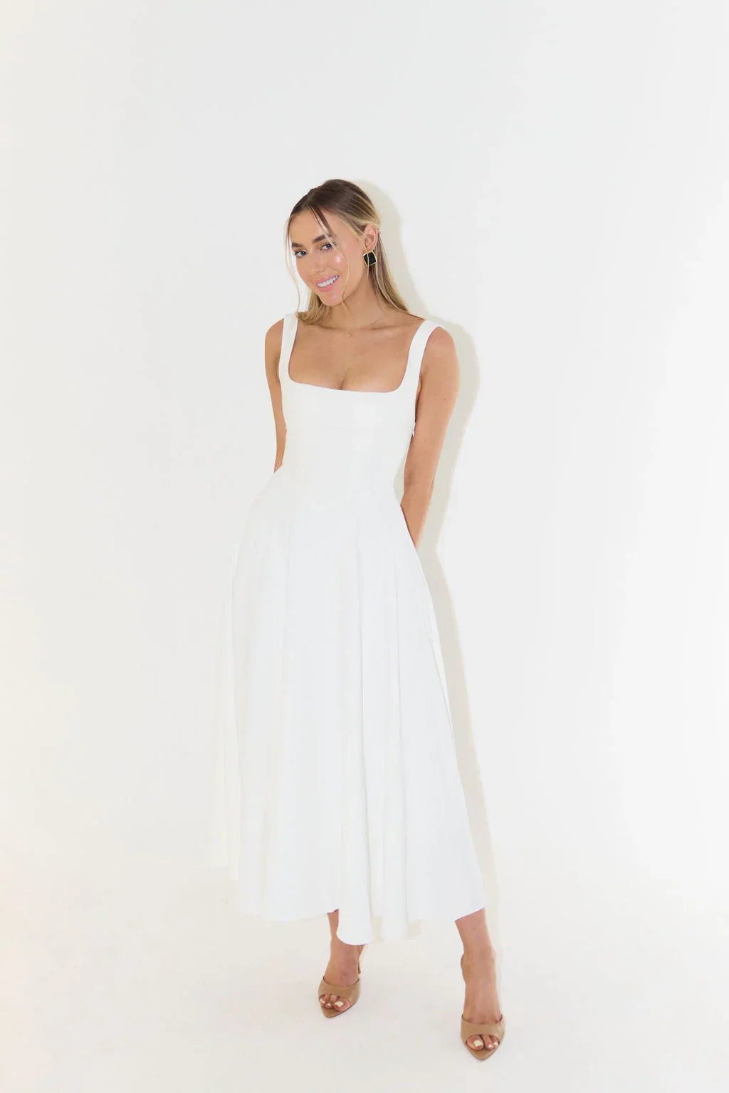 Women's white midi dress featuring a flattering square neck and flared silhouette.