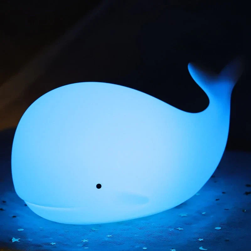 Squishy silicone whale lamp. Features soothing color-changing LED lights, ideal as a kids' night light or nursery decor.