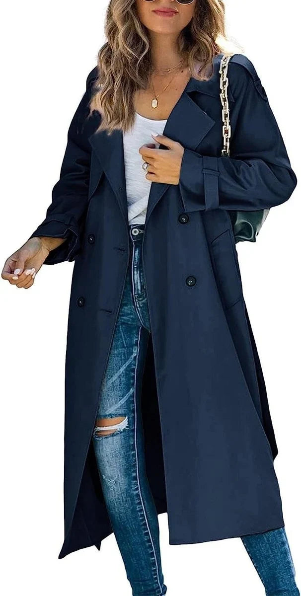 Full-length women's oversized double-breasted trench coat with tie belt, styled for an elegant fall look.