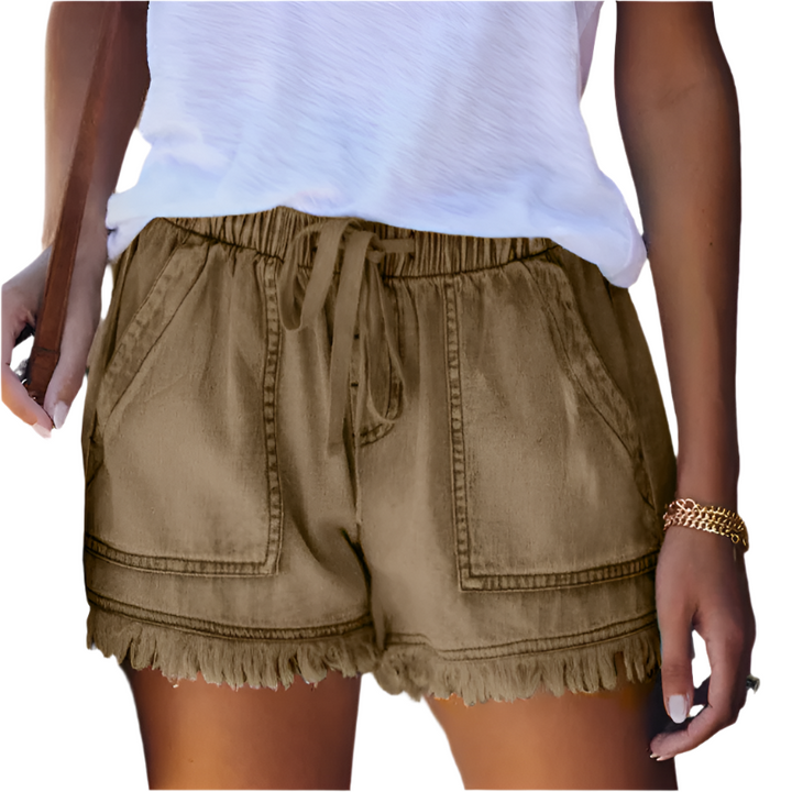 Close-up of fringe hem detailing on women's high-waisted denim shorts, highlighting unique summer style.