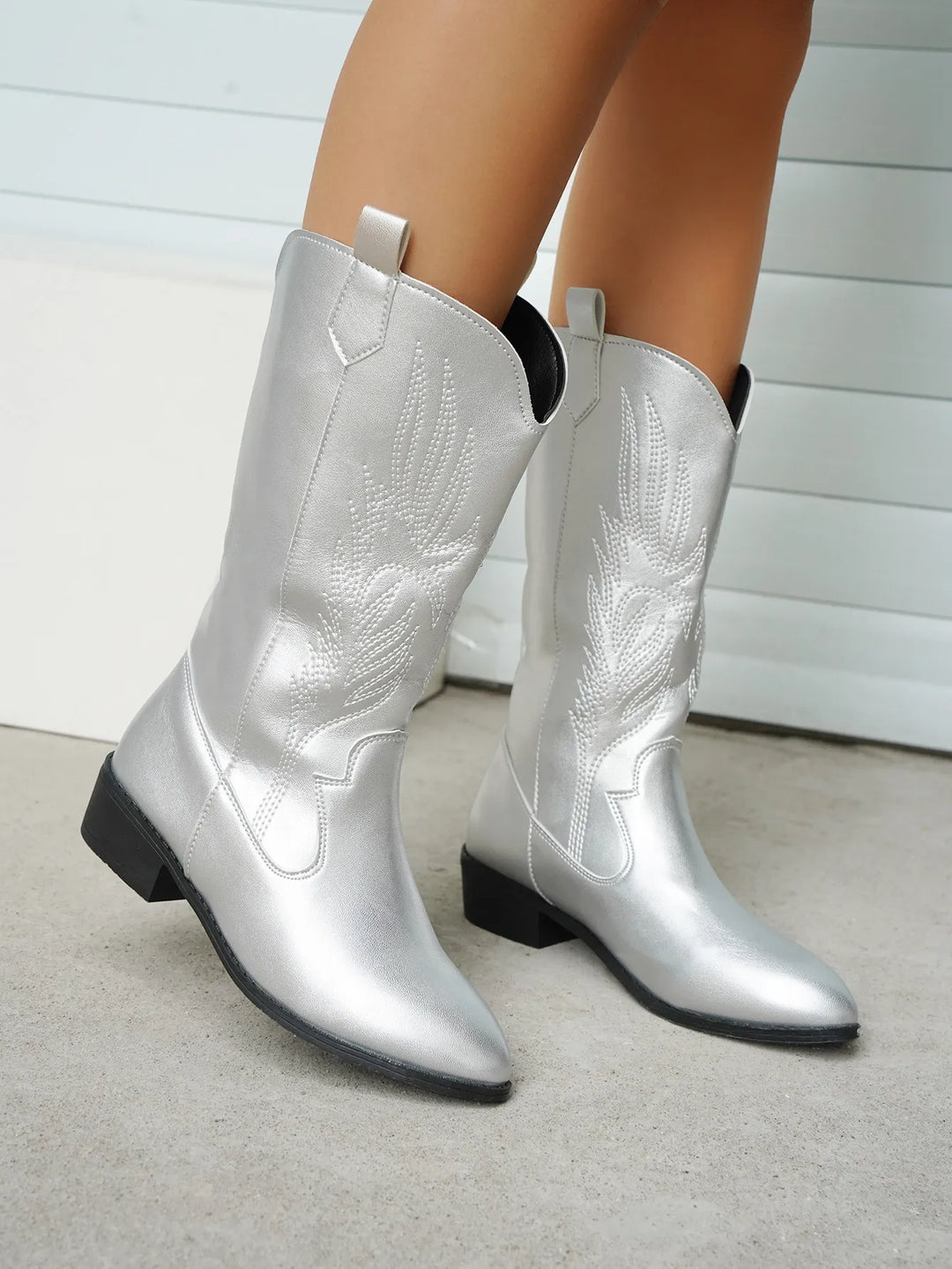 Side profile of women's western boots, elegant stitching detail, pointed toe, fashion footwear.