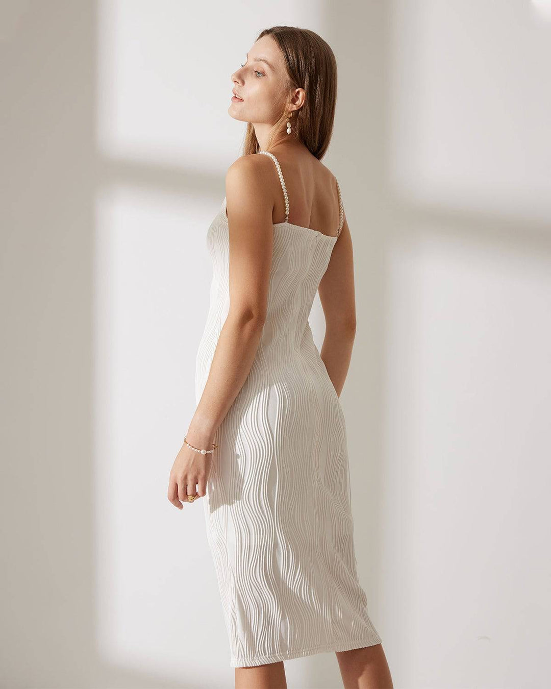 Elegant white cami midi dress for women, featuring a textured design & delicate pearl straps. Ideal for formal events.