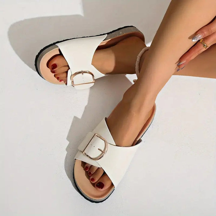 Black slip-on slide sandals for women. Features an open toe, contoured footbed, and adjustable buckle.