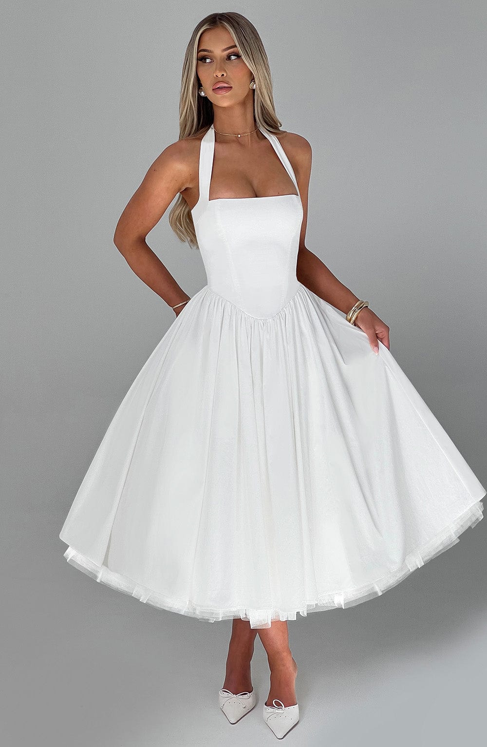 Graceful white midi dress featuring a halter neck and elegant flared hem.