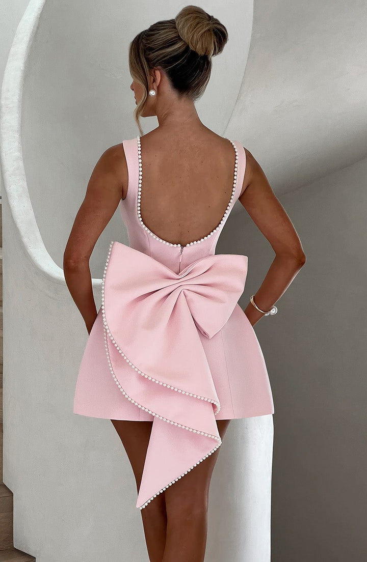 Short summer dress in pink, ideal for events, accented by a chic bow and pearl trim.
