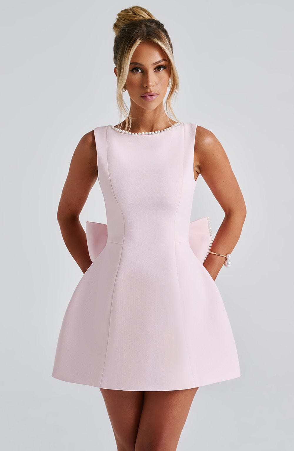Elegant women's black party dress featuring a feminine bow back and pearl embellishments.