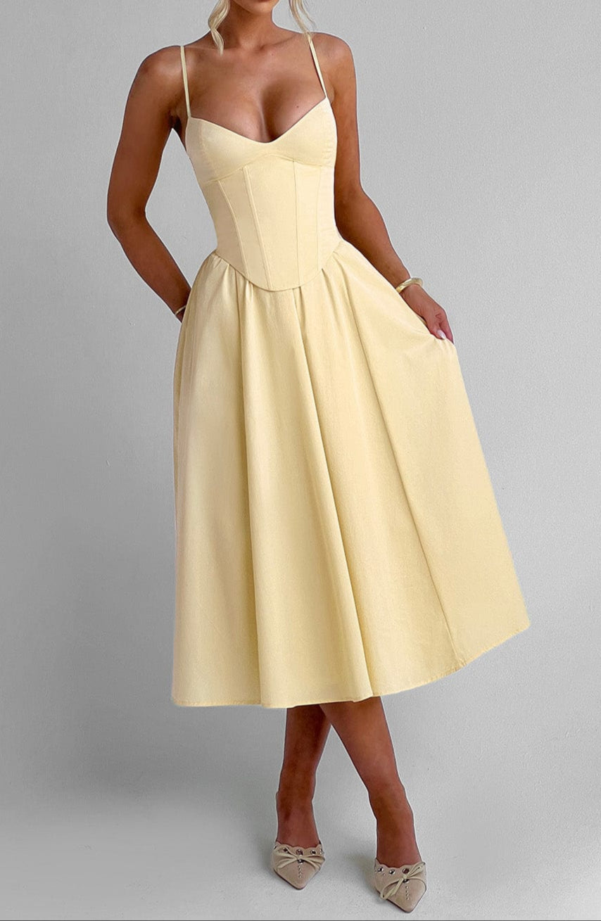 Close-up of yellow corset bodice on elegant midi dress. Features spaghetti straps, A-line cut. Ideal for formal events.