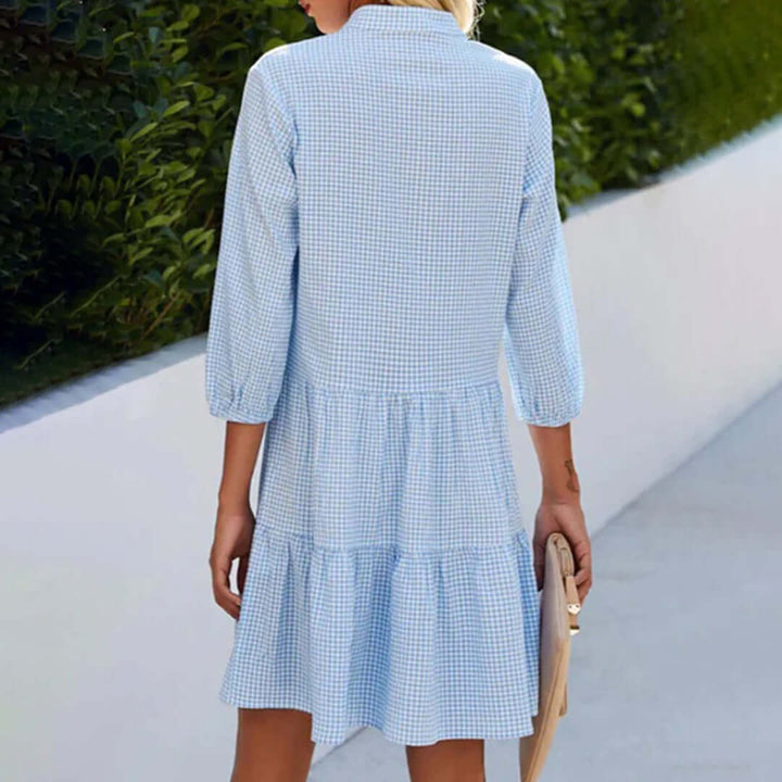 Close-up of women's blue gingham tiered button-down dress fabric & detail. Relaxed fit, ideal for spring garden parties.