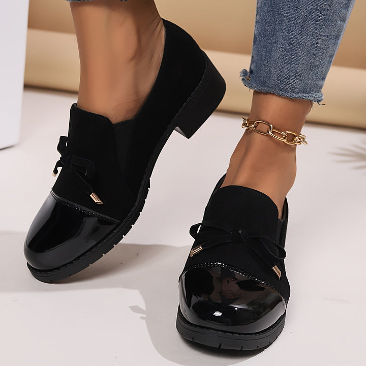 Comfortable women's loafers in black, designed with a sophisticated bow and easy slip-on style.