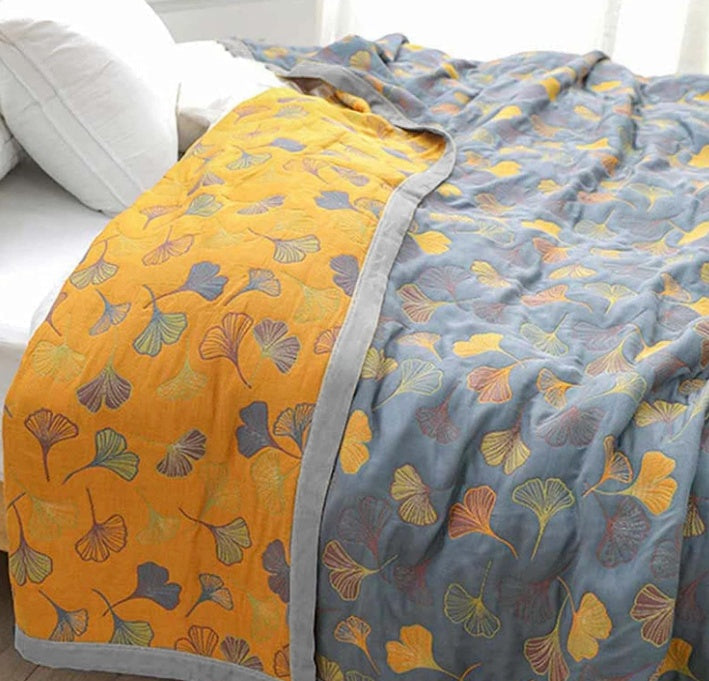 Plush ginkgo leaf throw blanket, reversible yellow & blue, adds botanical comfort to any home decor.