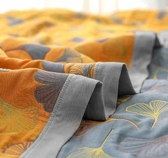 Decorative ginkgo leaf throw blanket, reversible yellow & blue, provides cozy comfort for living rooms.