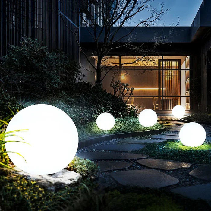 Night view of a garden path lit by the GlowSphere spherical light