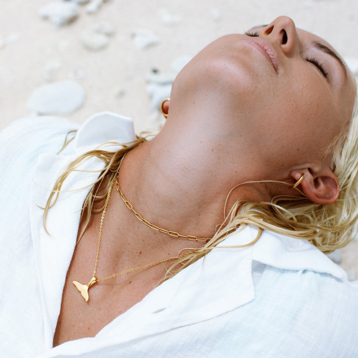 Gold whale tail pendant necklace, symbolizing ocean freedom and grace.