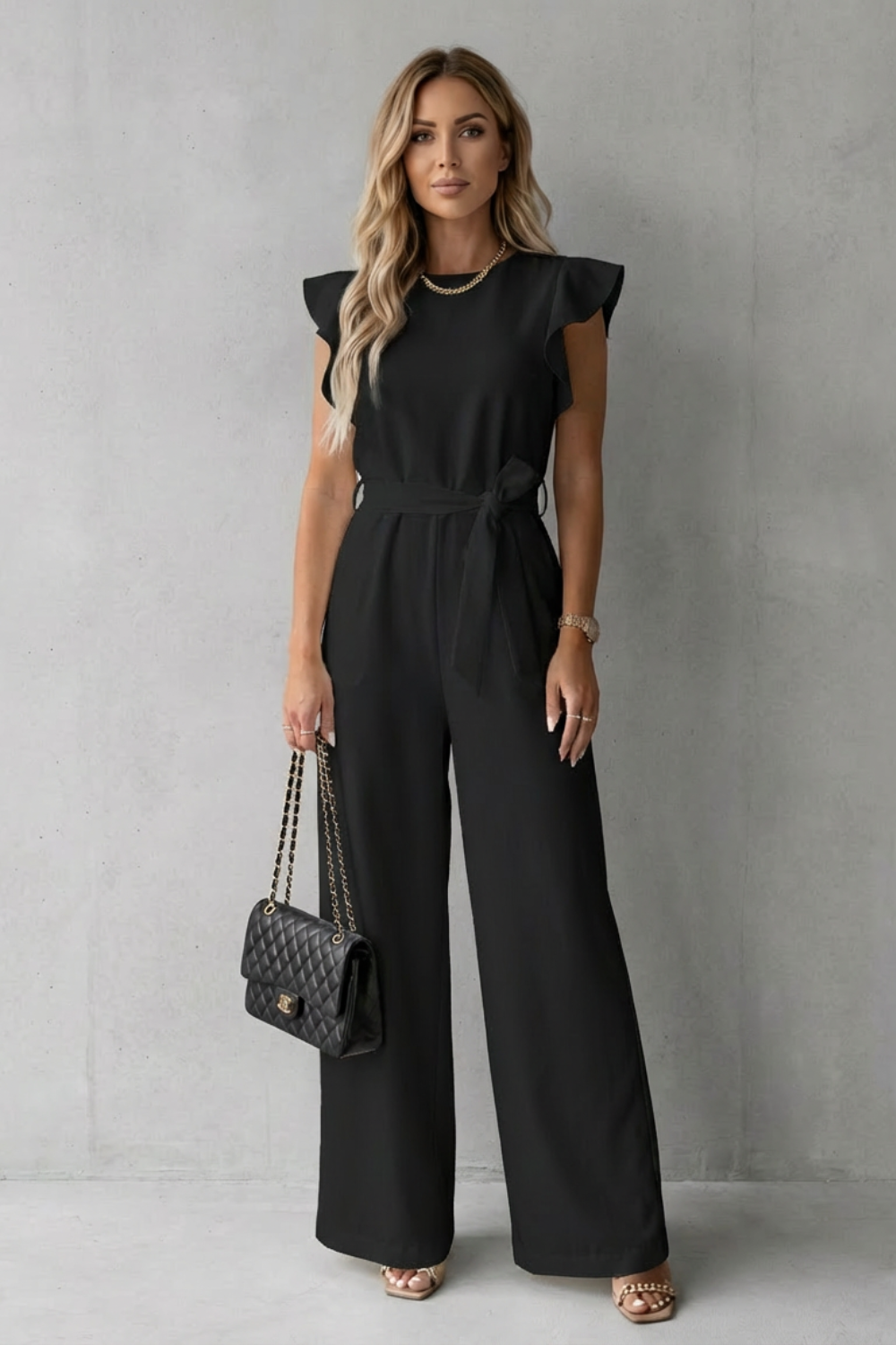Flattering silhouette of a women's wide-leg jumpsuit with elegant ruffle sleeves & a defined belt.