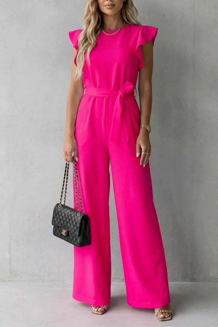 Woman in a flowing wide-leg jumpsuit with ruffle sleeves and belt, showcasing elegant movement.