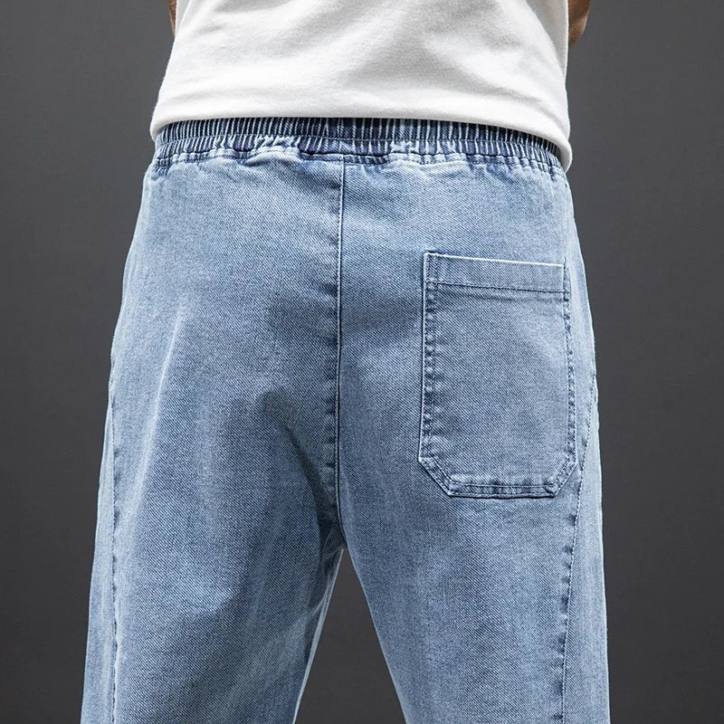 Modern men's blue stretch denim joggers with elastic waist and tapered leg for versatile, comfortable casual style.