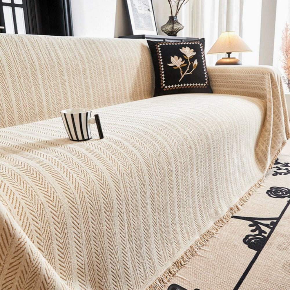 Herringbone chenille sofa cover with elegant tassels, protecting furniture from pets.
