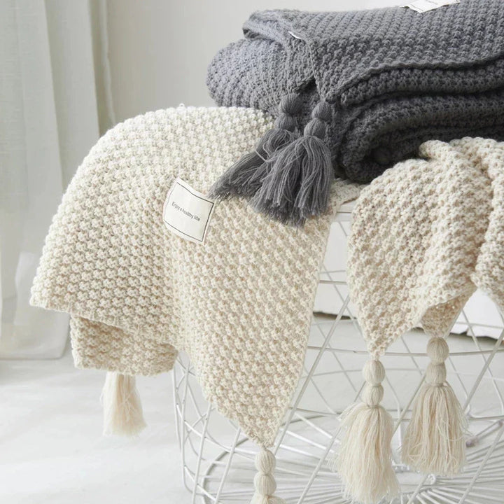 Beautiful knitted wool blanket with tassels, enhances any cozy home aesthetic.