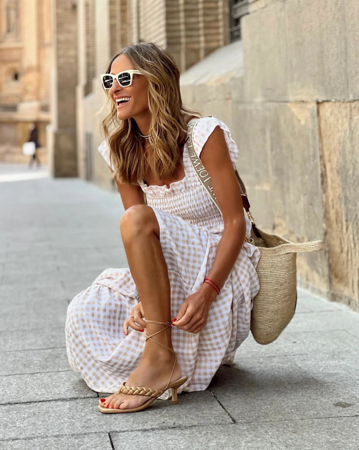 Blue gingham smocked maxi dress for women, featuring elegant flutter sleeves and a flowy tiered skirt.