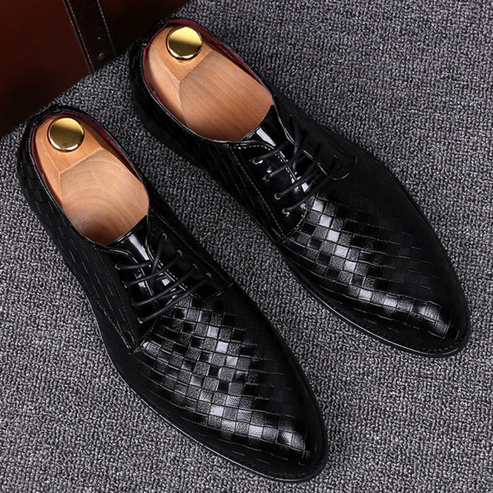 Close-up of detailed stitching on men's black leather lace-up formal footwear.