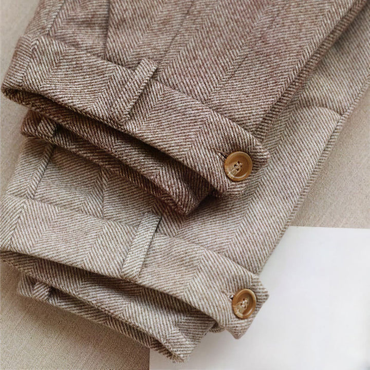 Detail shot of men's herringbone pleated trousers fabric. Quality, textured menswear.