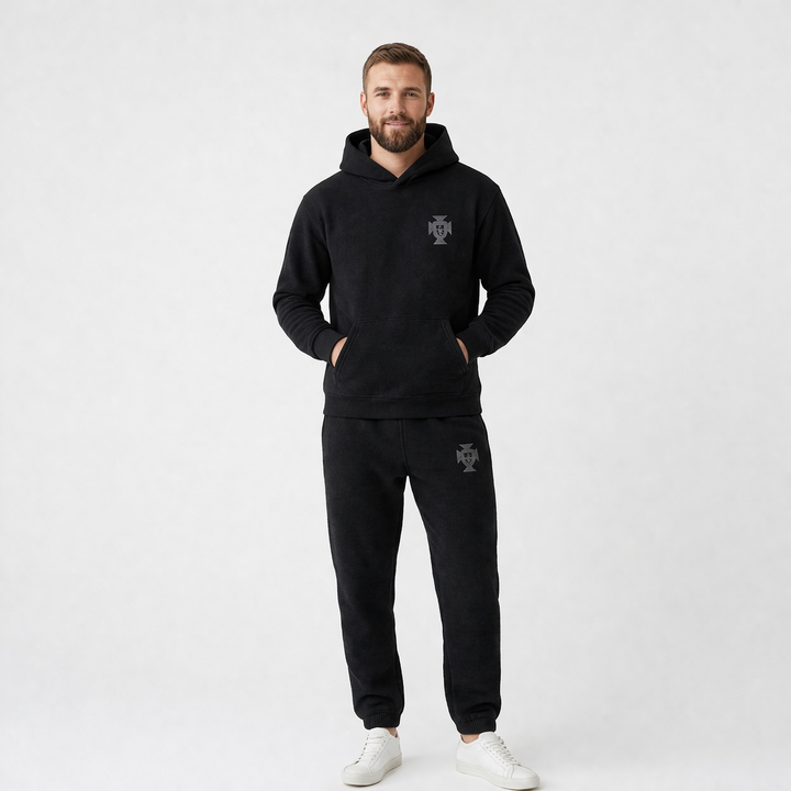 Side view of a man wearing a black hooded full body tracksuit for lounging.