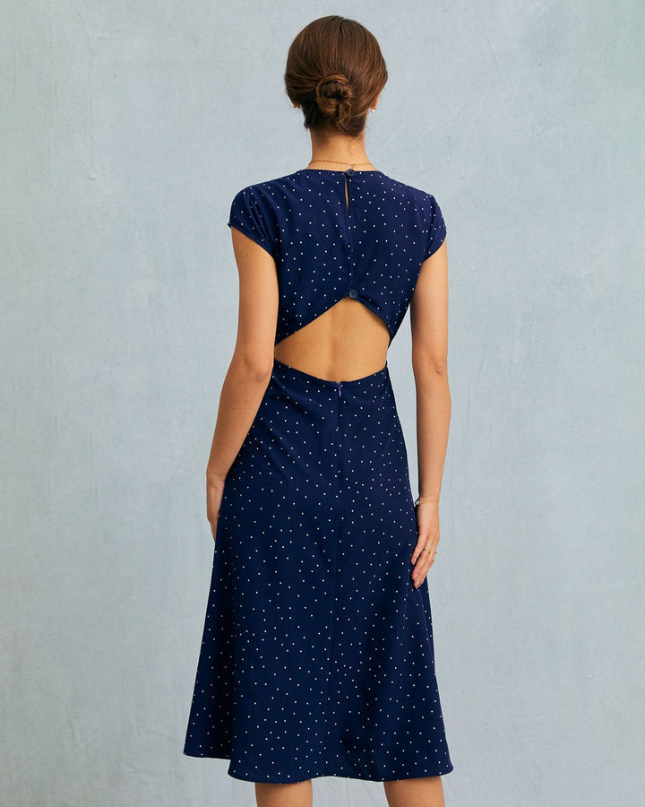 Navy blue polka dot midi dress with cap sleeves. This elegant women's dress features a stylish cut-out detail.
