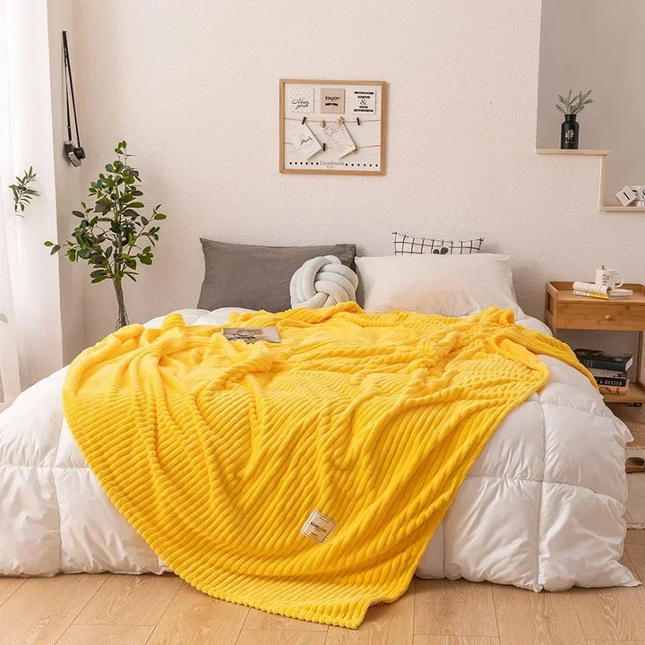 Ultra-soft flannel throw blanket on a bedroom bed, a warm & snug essential for restful comfort.