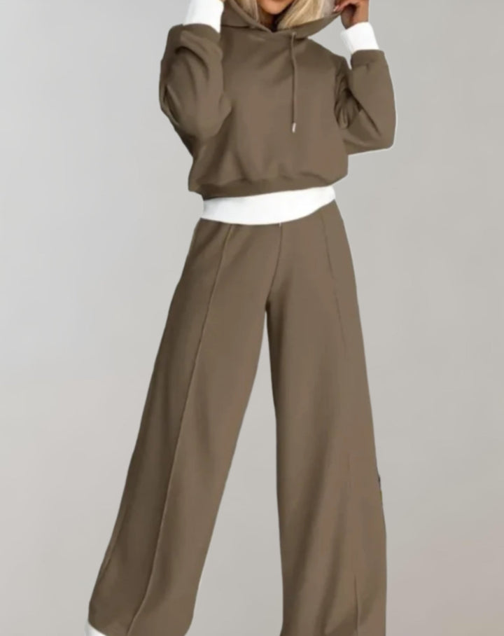 Fashionable women's travel outfit: a cozy two-piece tracksuit with a hooded top and wide-leg pants.