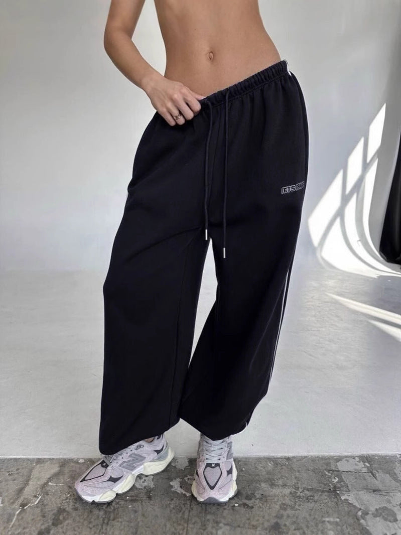 Close-up of women's baggy sweatpants showing the side stripe and drawstring closure.
