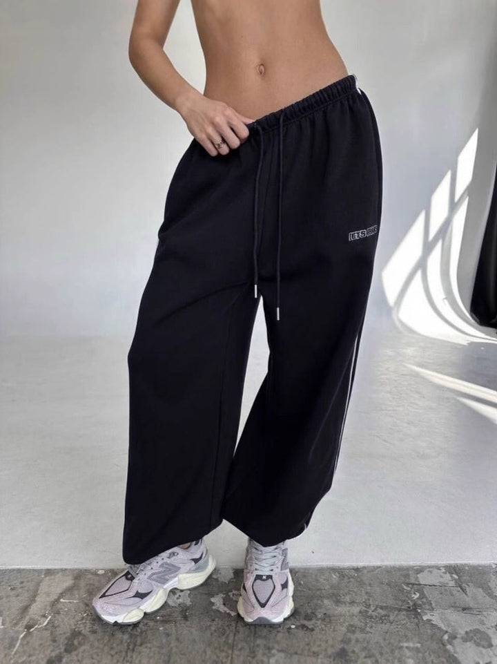 Close-up of women's baggy sweatpants showing the side stripe and drawstring closure.
