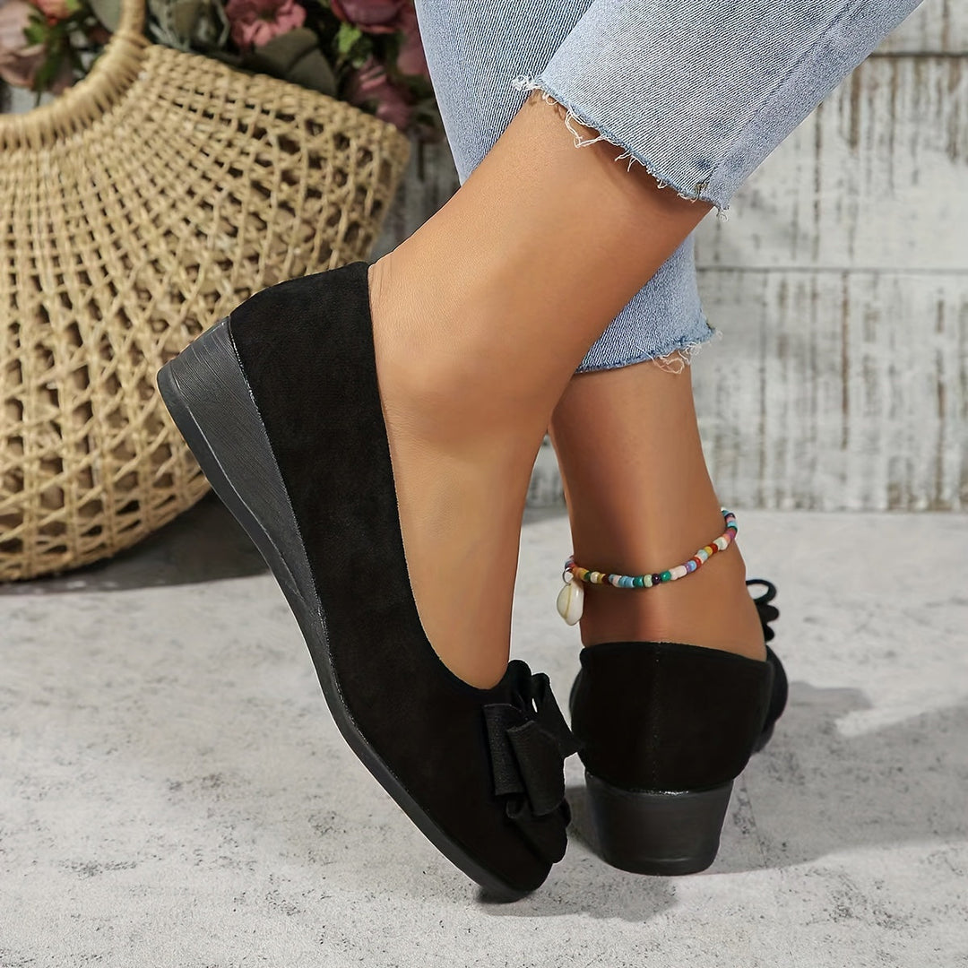 Classic women's wedge flats featuring a charming bow, offering effortless slip-on comfort.