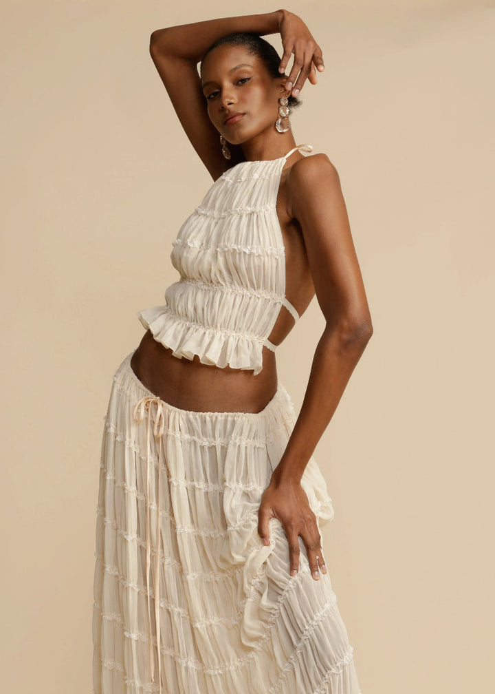 White women's comfortable two-piece summer set featuring a chic halter top and flowy maxi skirt.