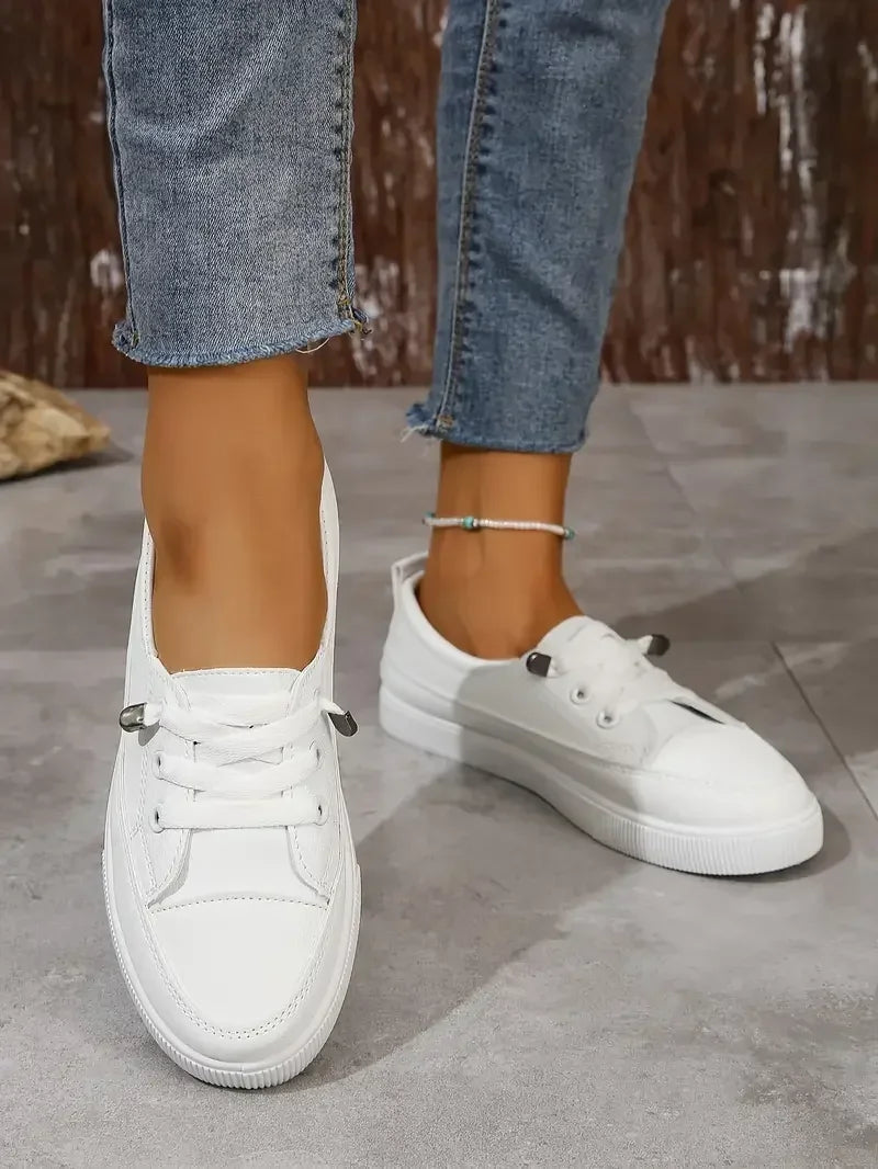Stylish women's low-top lace-up sneakers. White casual flats offering comfortable footwear for everyday style.