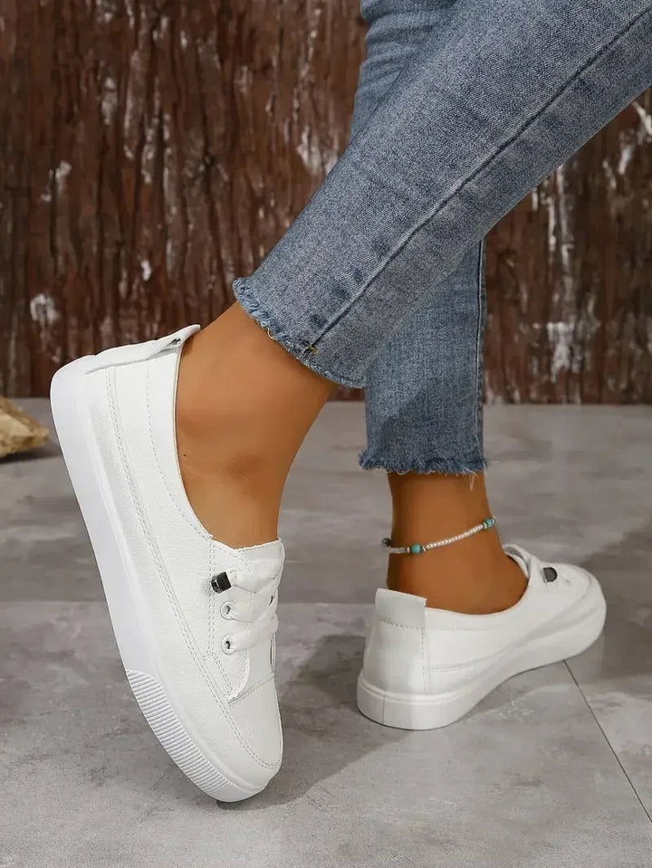 Classic white women's lace-up sneakers. Casual low-top flats providing everyday comfort for stylish walking.
