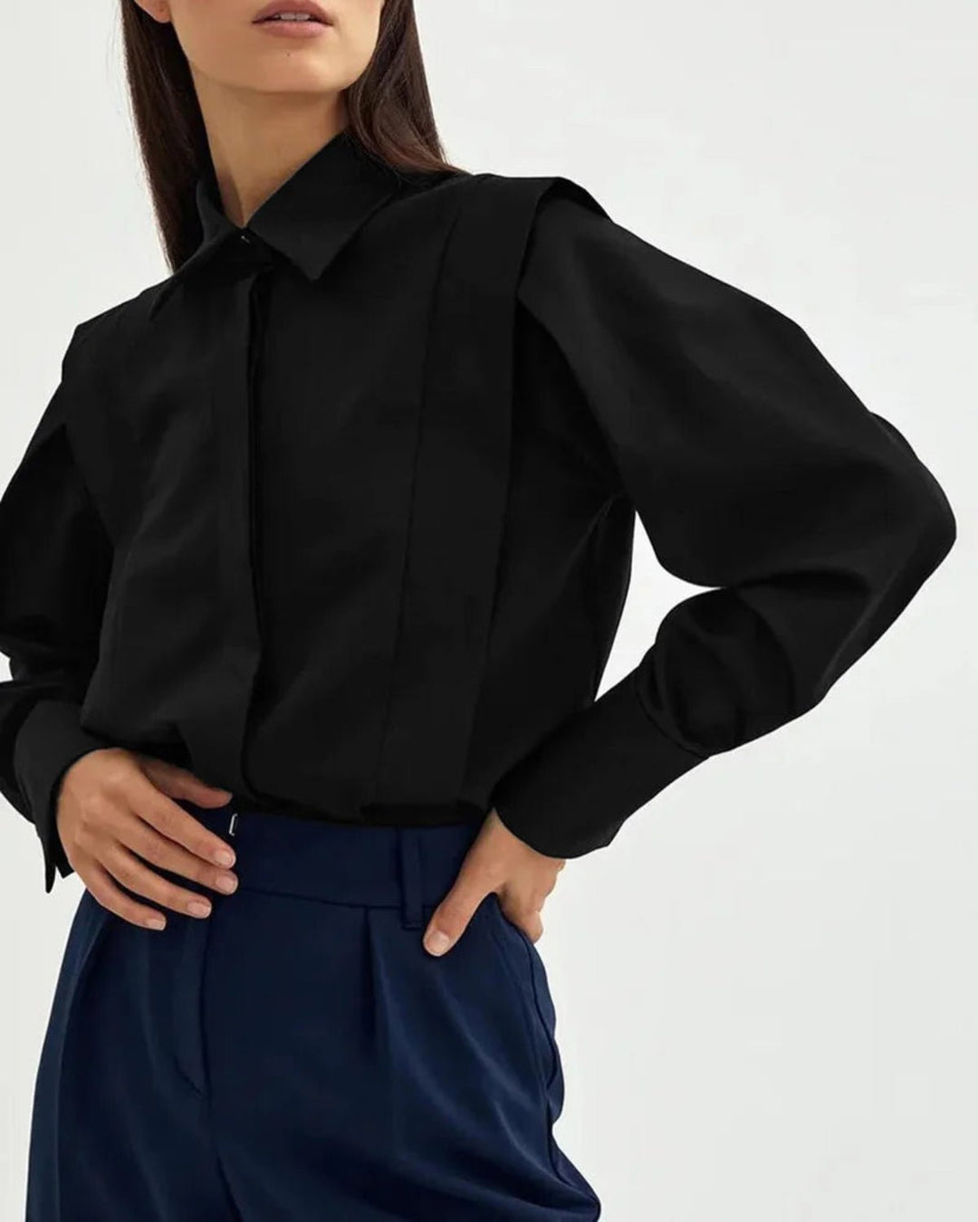 A woman holding the sleeve of a versatile women's button-down blouse.