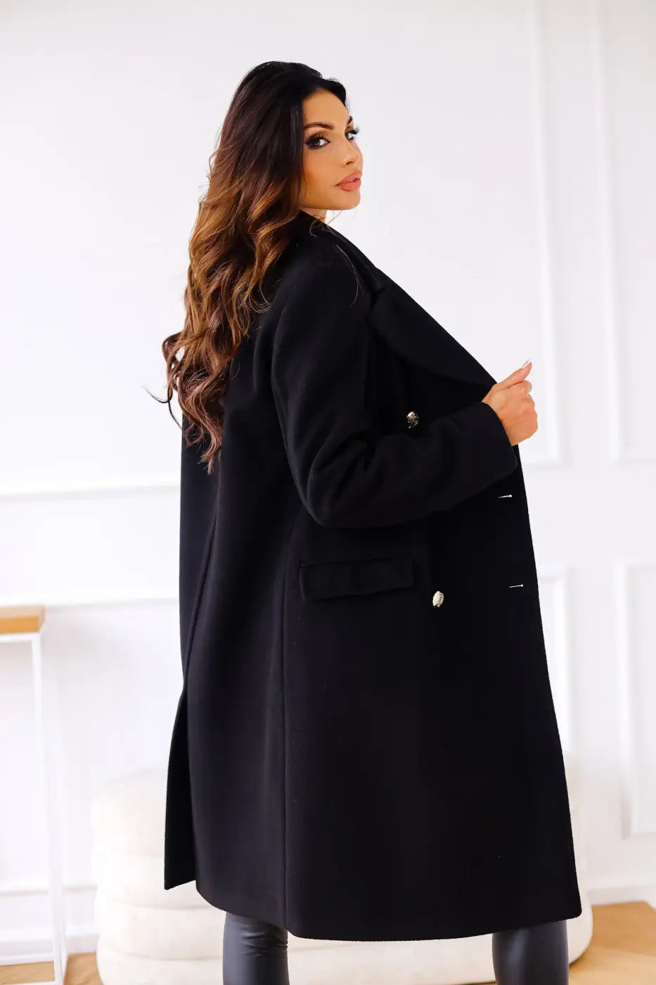 Sophisticated women's long tailored coat, double-breasted, with polished gold button detailing.