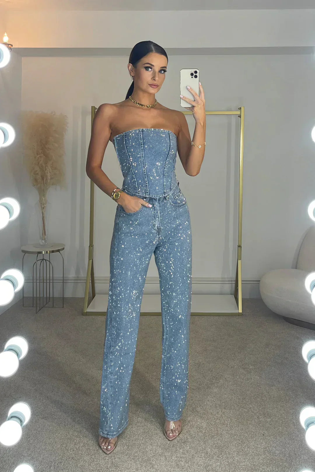 Detail shot of glittering fabric on women's high-waist jeans & shimmering top set. Trendy party wear.