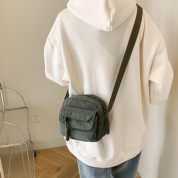 Modern women's crossbody bag with a textured finish and zip pocket.