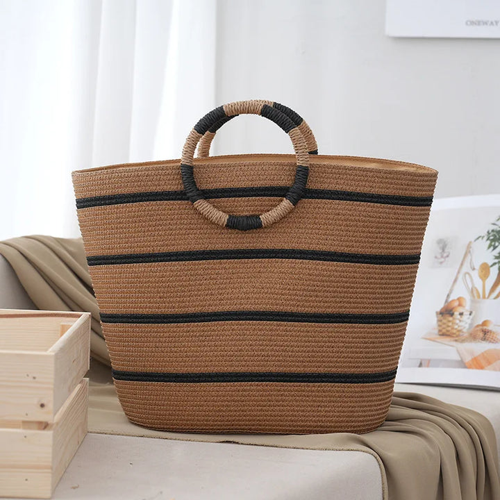 Fashionable women's striped canvas tote bag with unique woven rope handles, great for summer beach days & casual outfits.