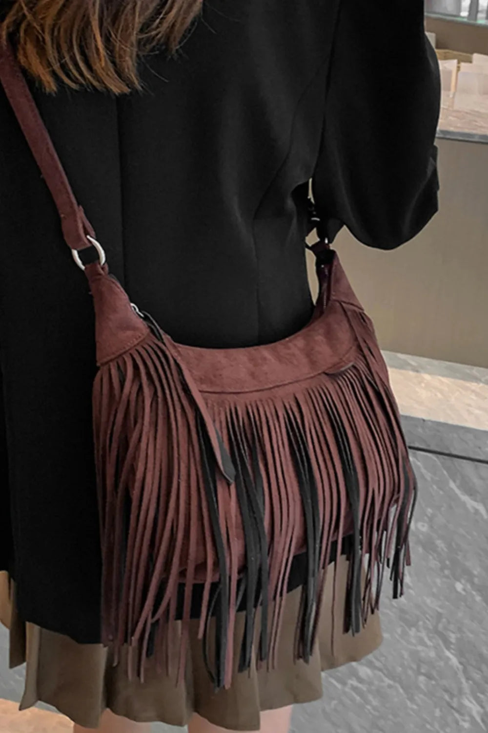 Suede fringe detail cascading down a boho shoulder bag.