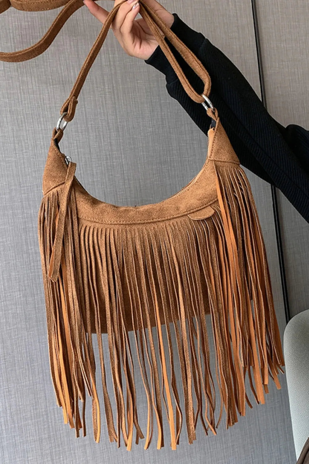 Close-up of intricate fringe detail on a women's boho suede handbag.